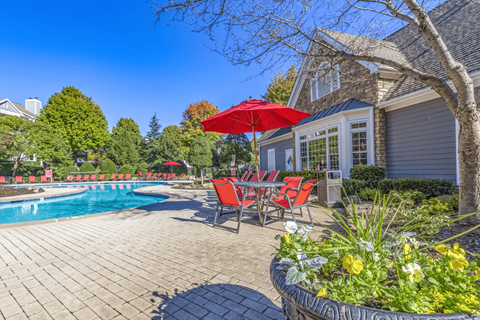 a patio next to a pool with a table and chairs and a umbrella at Elan at Mallard Creek Apartment Homes, Charlotte