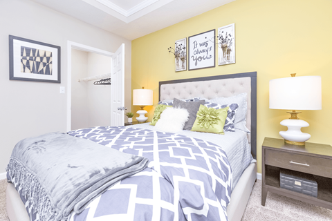 a bedroom with yellow walls and blue and white bedding at Elan at Mallard Creek Apartment Homes, North Carolina