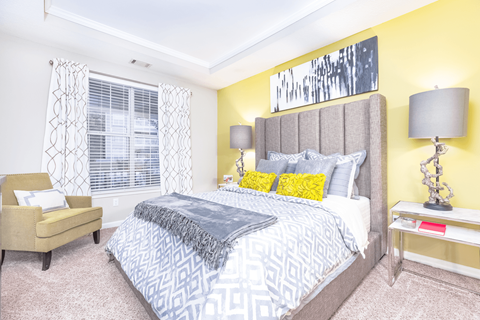 a bedroom with yellow walls and a large bed at Elan at Mallard Creek Apartment Homes, Charlotte, NC