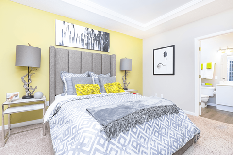 a bedroom with yellow walls and a gray bed at Elan at Mallard Creek Apartment Homes, Charlotte, 28269