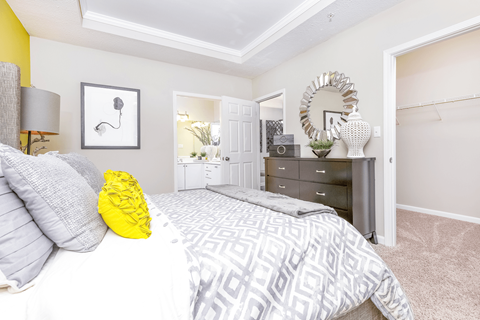 a bedroom with a large bed and a dresser with a mirror at Elan at Mallard Creek Apartment Homes, North Carolina, 28269