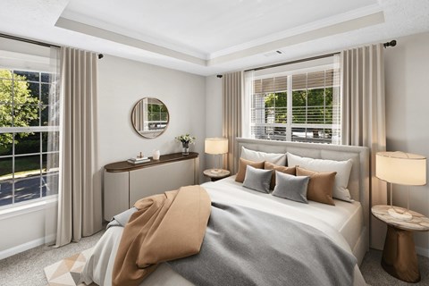 A bedroom with a large bed, a round mirror, and a window with blinds at Elan at Mallard Creek Apartment Homes, North Carolina