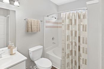 A white bathroom with a toilet, sink, and shower curtain at Elan at Mallard Creek Apartment Homes, Charlotte, NC, 28269