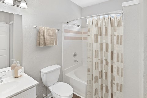 A white bathroom with a toilet, sink, and shower curtain at Elan at Mallard Creek Apartment Homes, Charlotte, NC