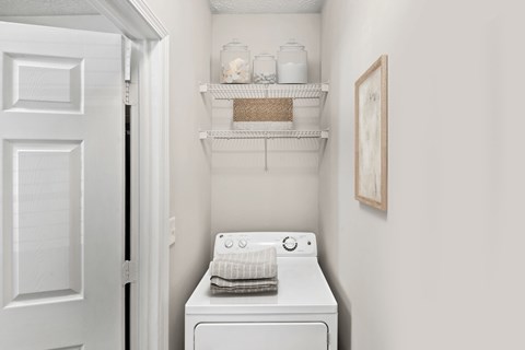 A white washing machine sits in a small laundry room at Elan at Mallard Creek Apartment Homes, Charlotte