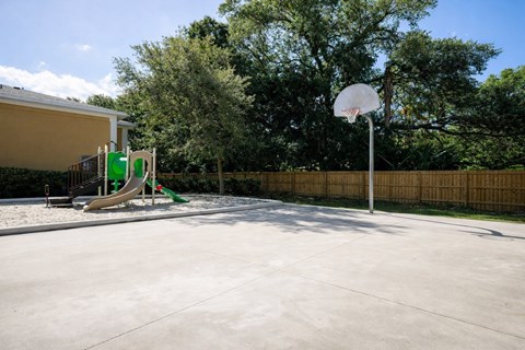 A basketball court with a basketball hoop and a slide in the background.