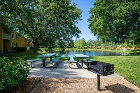 Picnic tables and bench are set up near a lake.