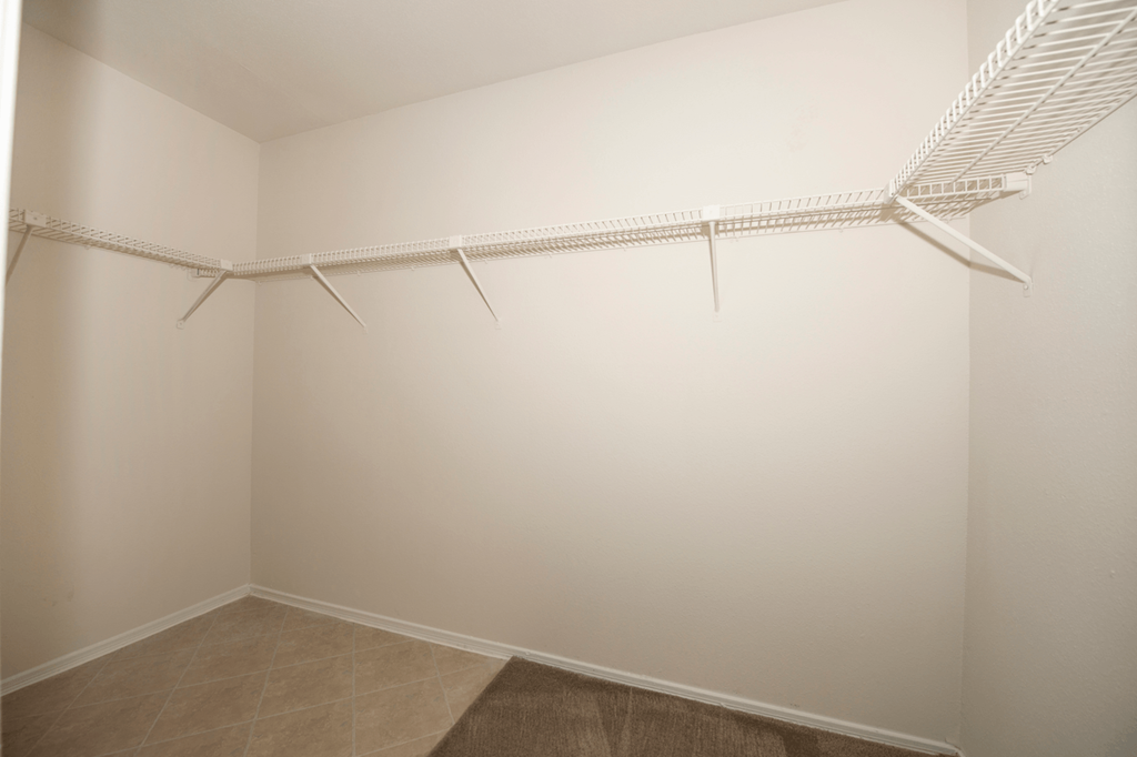 an empty closet with white walls and a white rack on the wall