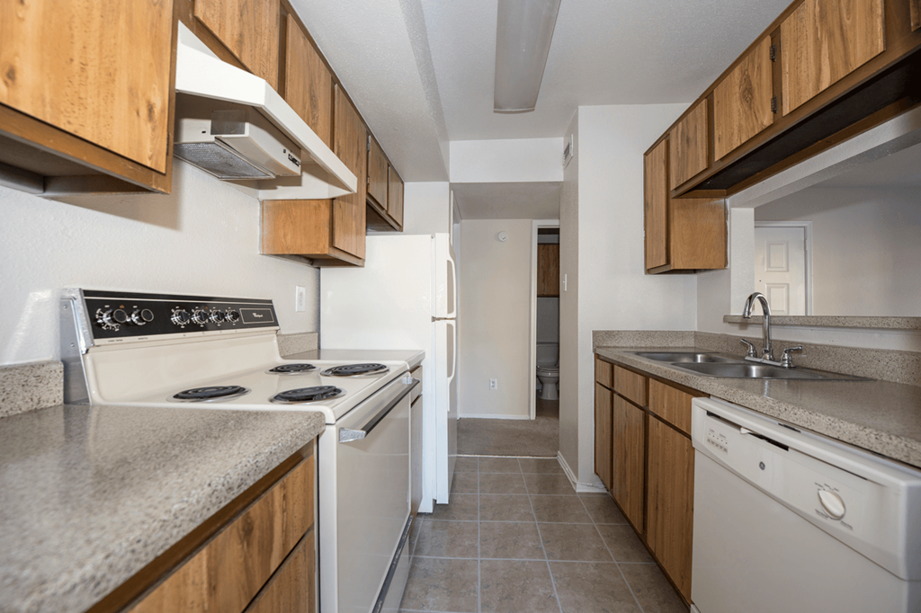 an empty kitchen with white appliances and wood cabinets