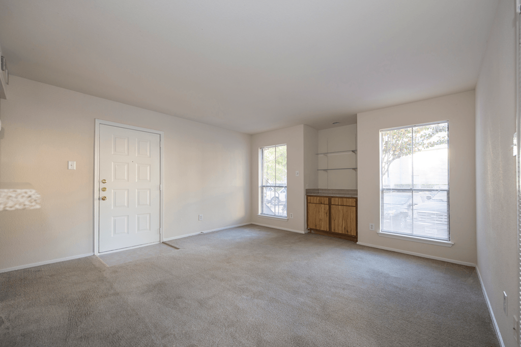 an empty living room with a white door and window