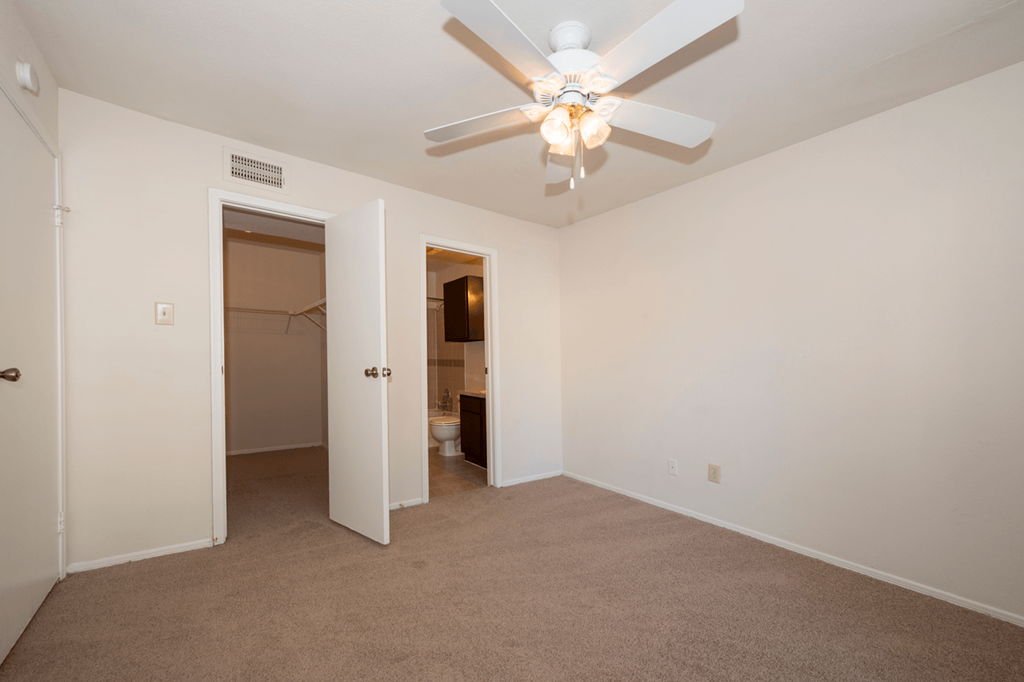 an empty living room with a ceiling fan and a closet