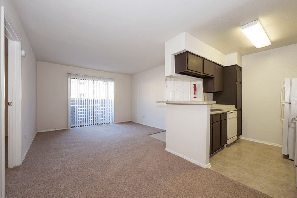 an empty living room and kitchen with a door to a balcony