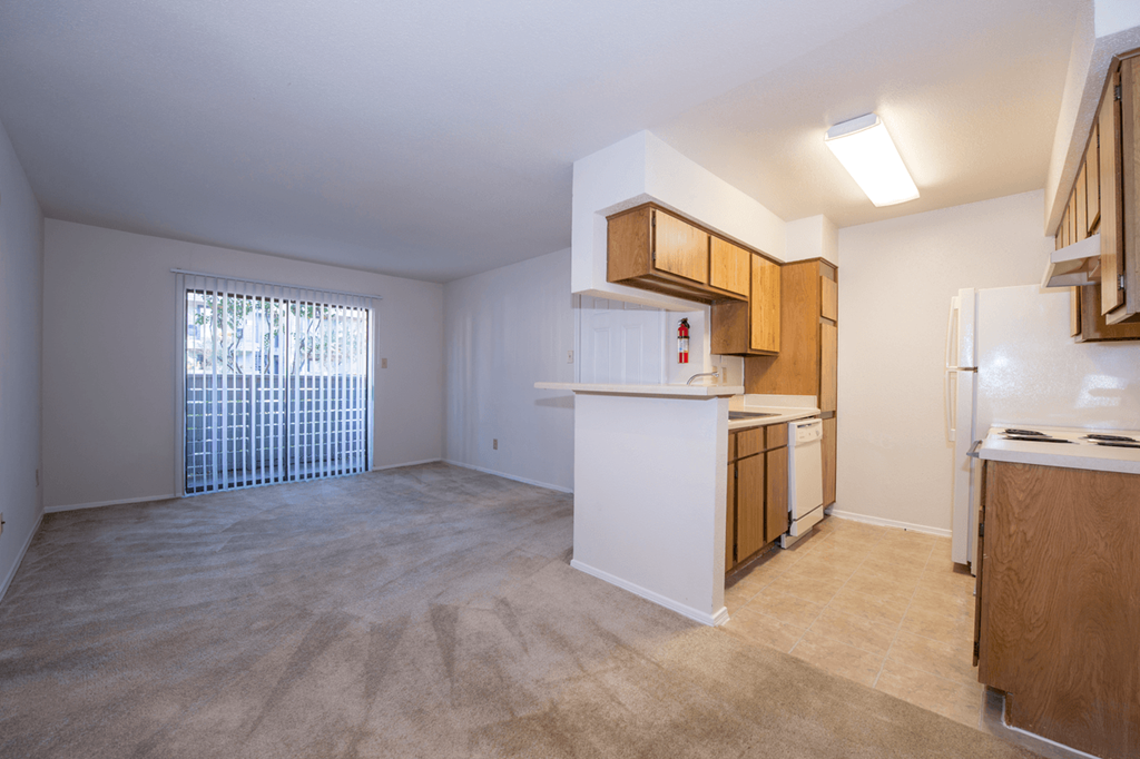 an empty kitchen and living room with a door to a balcony