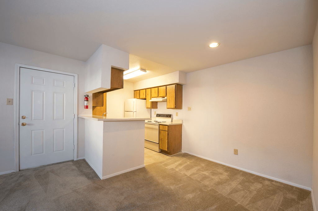 the living room and kitchen of a home with a white door