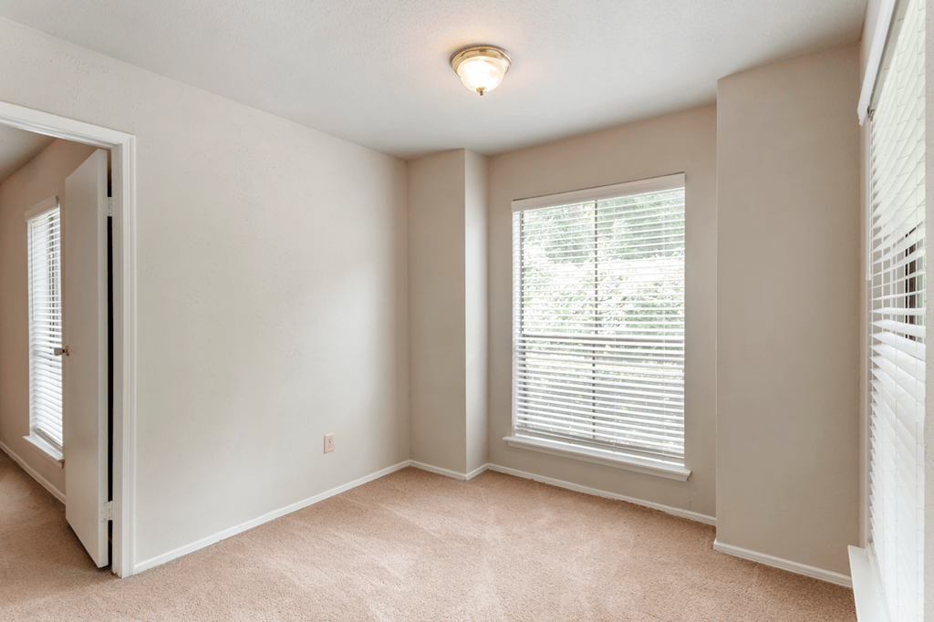 an empty living room with a large window and blinds