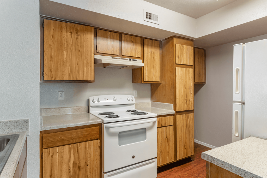 an empty kitchen with white appliances and wooden cabinets