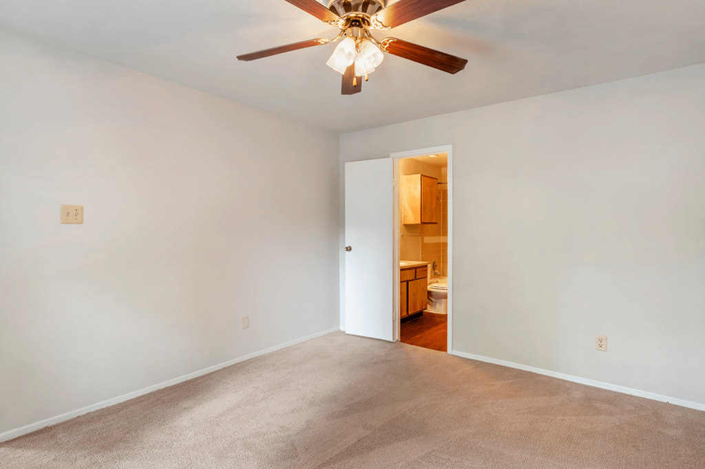 an empty living room with a ceiling fan and white walls