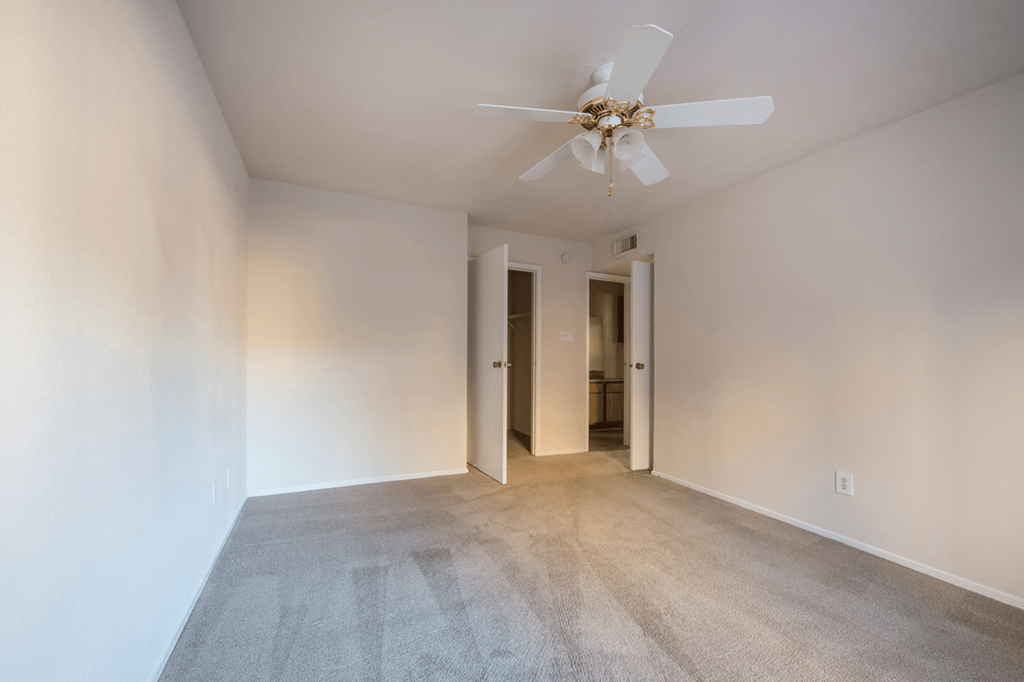 a living room with white walls and a ceiling fan