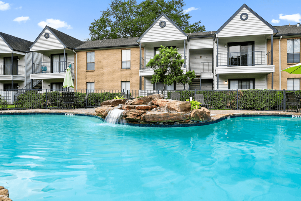 a large pool with a waterfall in front of an apartment building