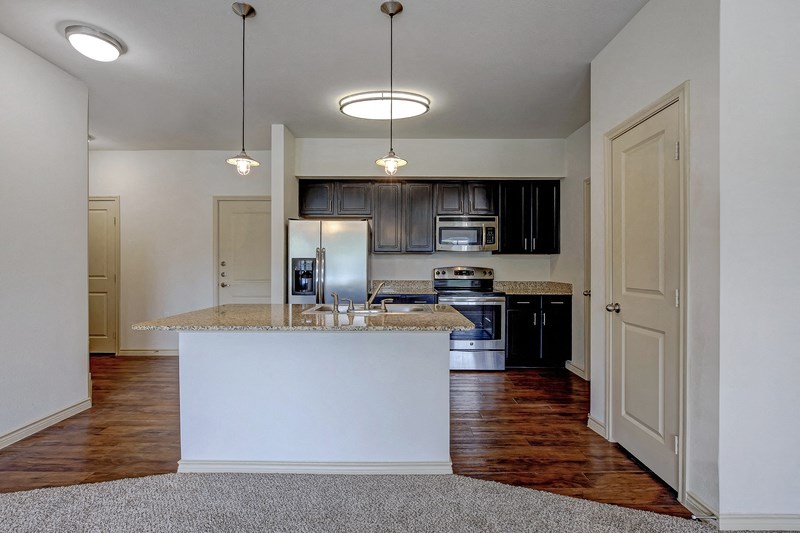 an empty kitchen with a marble counter top
