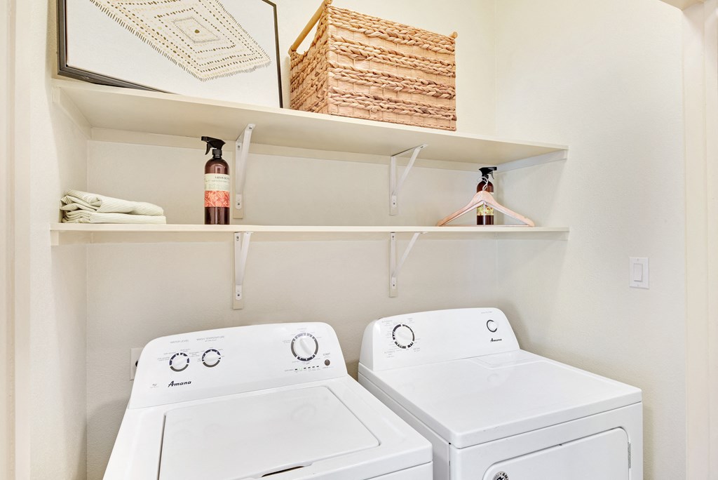 a washer and dryer in a laundry room with a shelf above them