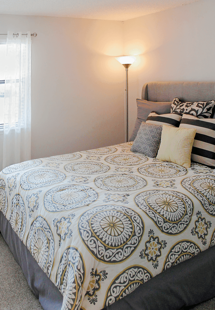 a bedroom with a bed and a lamp and a window