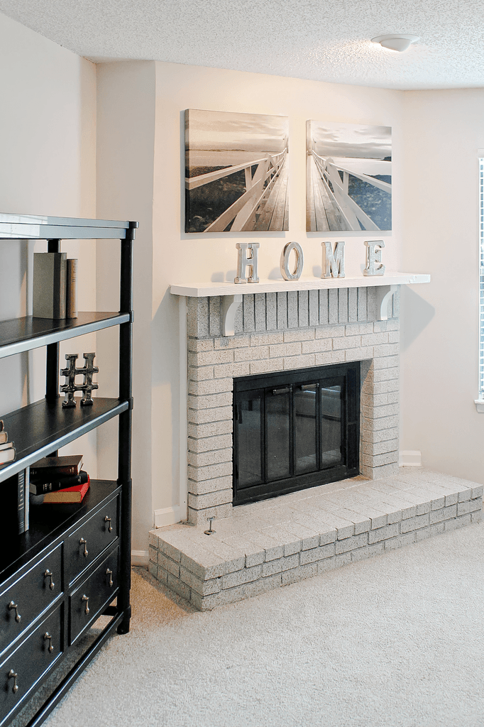a living room with a brick fireplace and two pictures on the wall