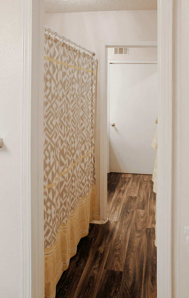 a bathroom with a shower curtain and a wood floor
