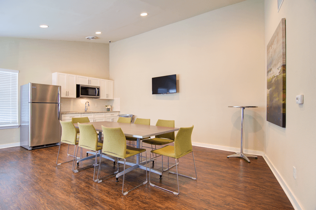 a conference room with a table and chairs and a kitchen with a refrigerator