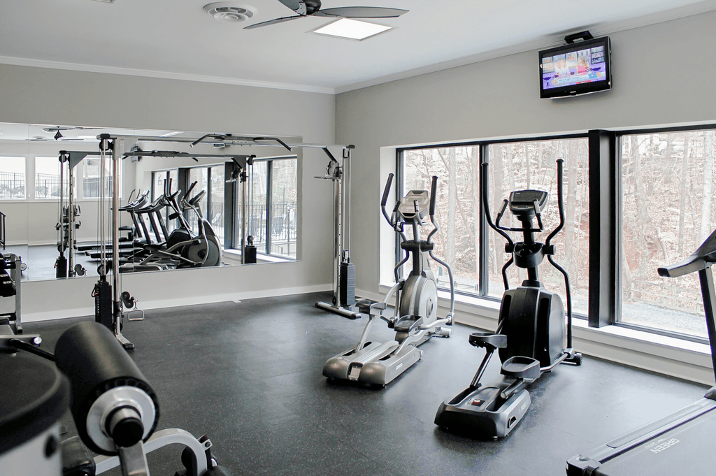 a gym with cardio machines and a tv on the wall