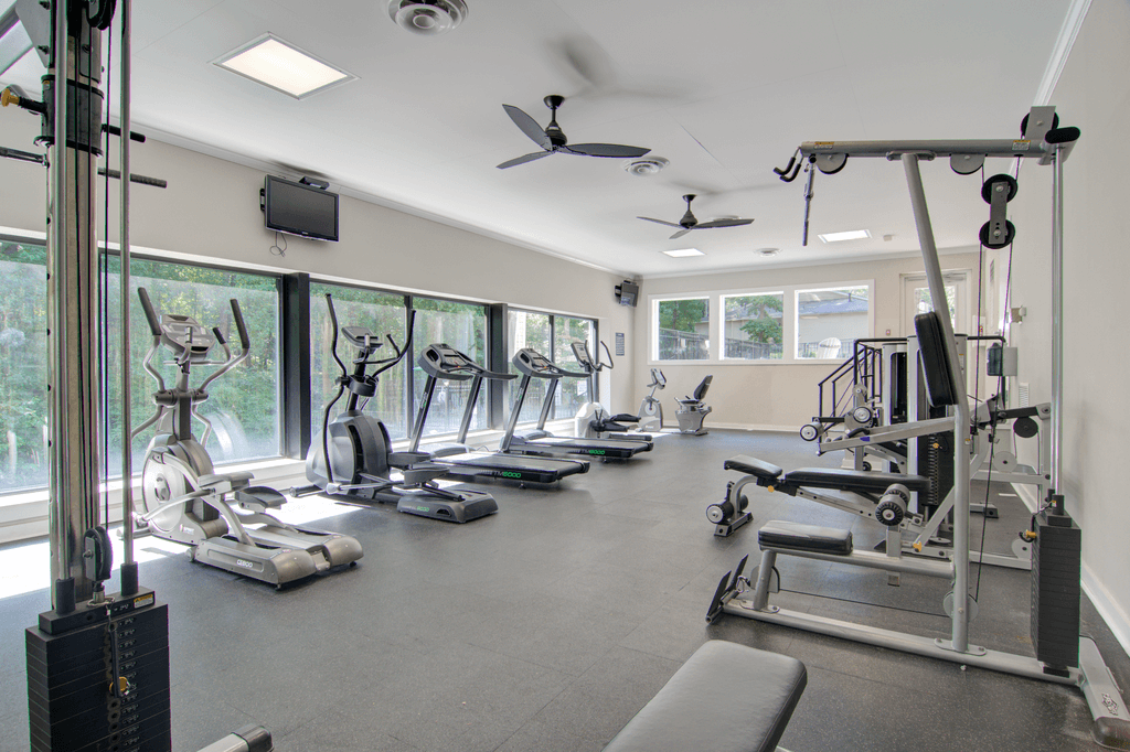 a gym with weights and cardio equipment and windows