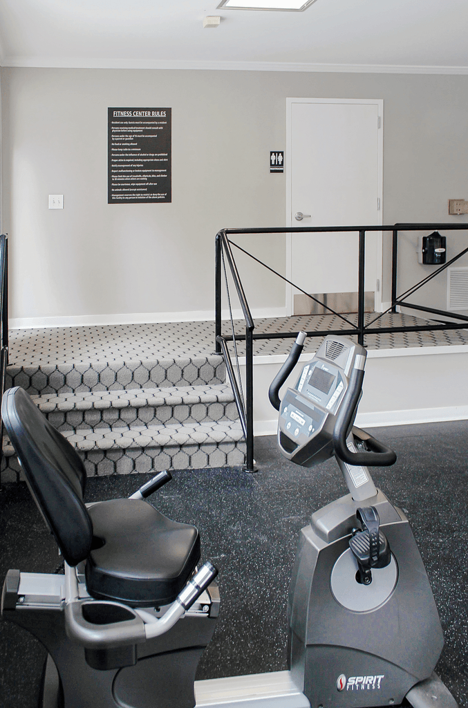 a gym with a treadmill and a chair in the corner of a room