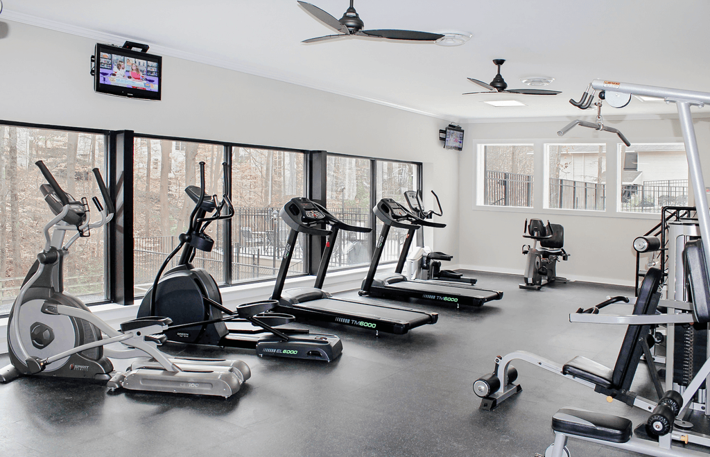 a gym with treadmills and other exercise equipment and a tv on the wall
