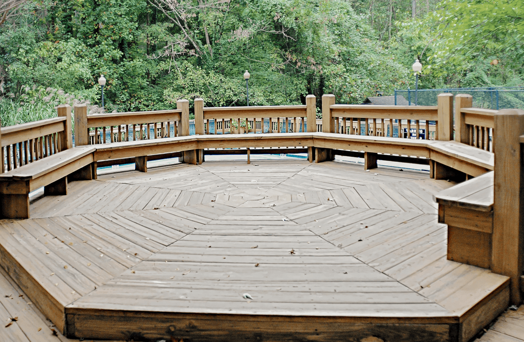 a deck with a wooden railing and a pond