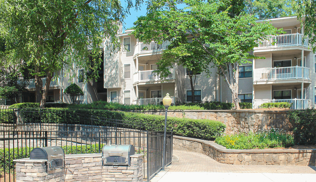 a view of an apartment building with trees and a fence