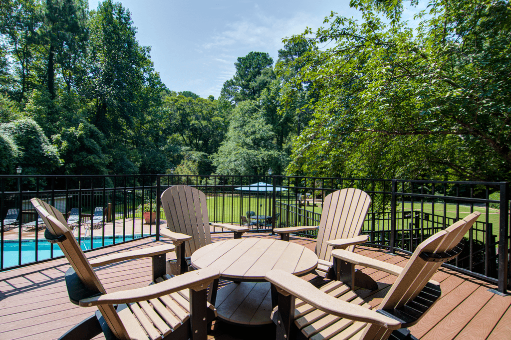 a patio with chairs and a table on a deck next to a pool