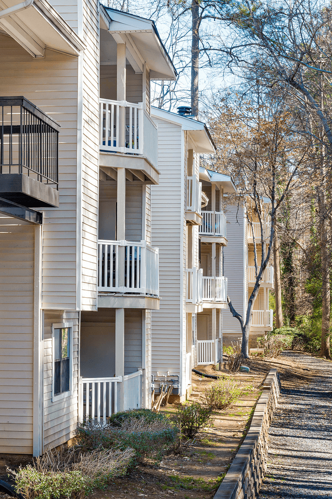 a row of white apartment buildings with trees in the background
