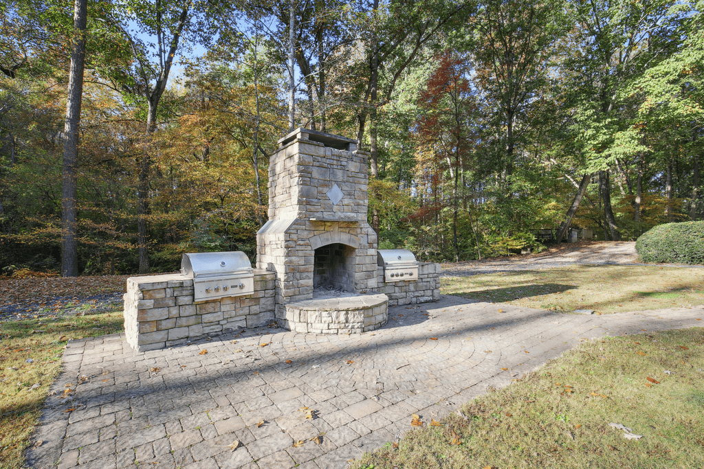 an outdoor stone fireplace with a stone bench next to a driveway