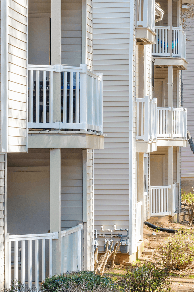 an apartment building with white vinyl siding and a balcony