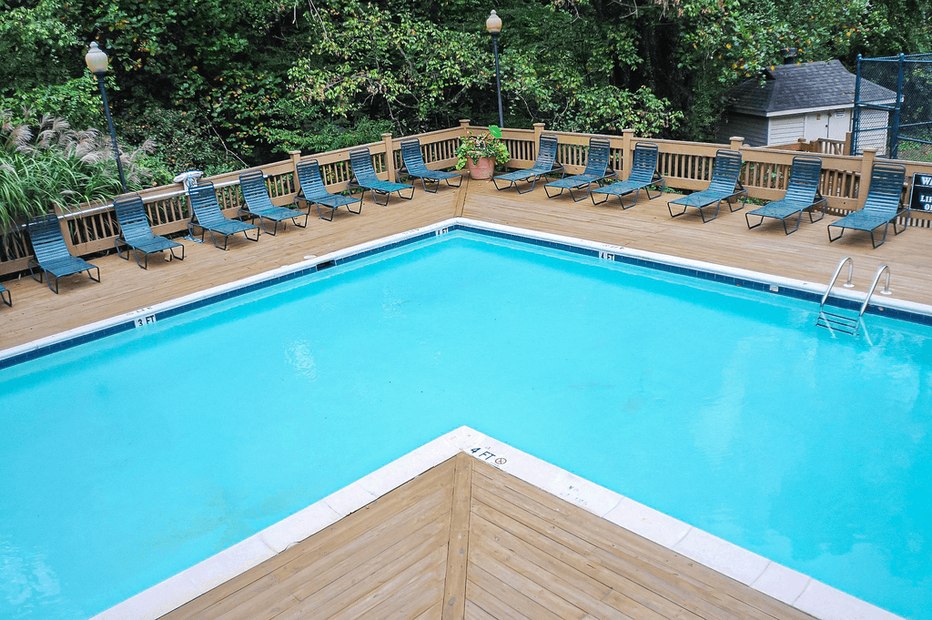 a swimming pool with wooden decking and chairs around it