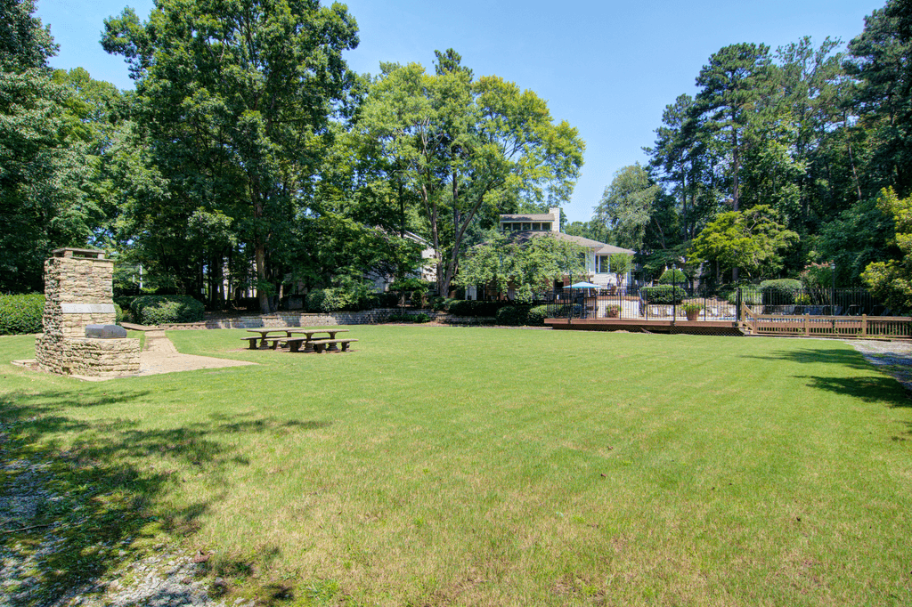 a park with a grass field and a house in the background