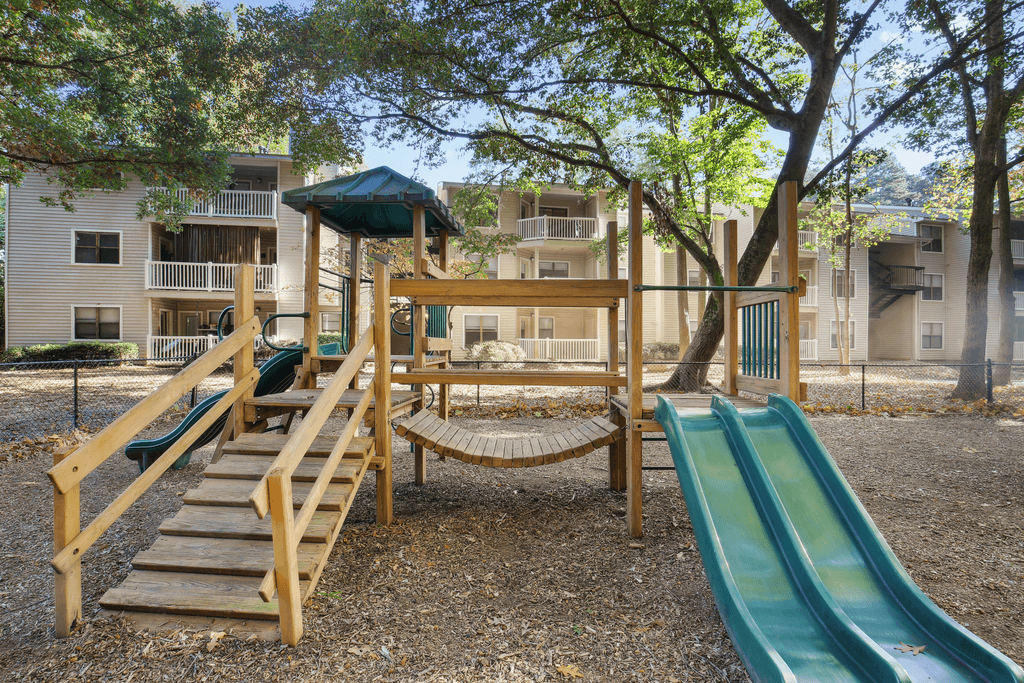 a playground with a swing set and slides at an apartment complex