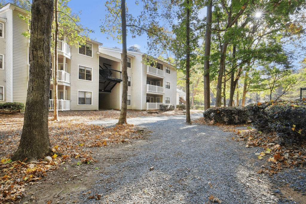 exterior view of the apartment building with trees and gravel pathway