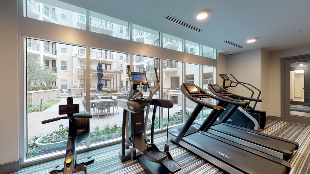 Fitness center facing treadmills and stair climber next to exterior window