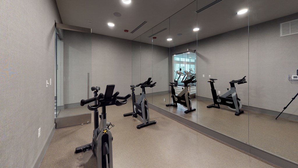 Spin/flex studio facing three exercise bicycles and a large mirror.