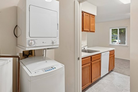 A white dishwasher is in a kitchen with wooden cabinets.