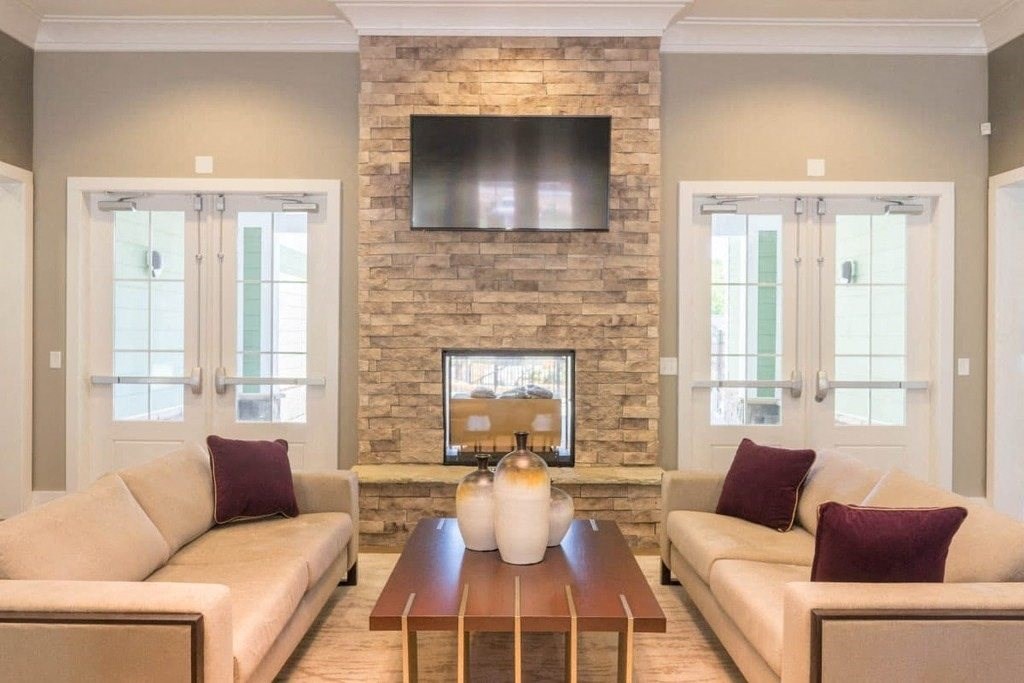 A living room with a stone fireplace and a flat screen TV mounted above it at Foxwood Apartments, Raleigh-Durham, North Carolina
