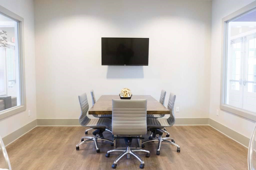 A conference room with a table, chairs, and a television mounted on the wall at Foxwood Apartments, Raleigh-Durham, 27616