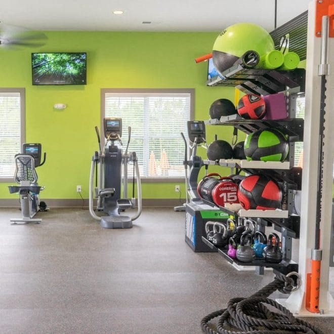 A gym with a green wall and exercise equipment at Foxwood Apartments, North Carolina, 27616