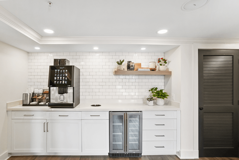 A modern kitchen with white cabinets and a black coffee maker.